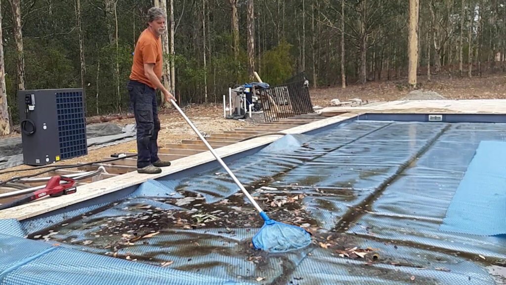 sweeping leaves from a pool cover